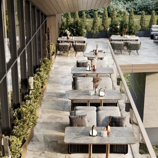 Terraza moderna con mesas y sillas dispuestas para cenas al aire libre, rodeada de vegetación.