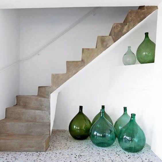 Escalera de cemento con botellas de vidrio verdes y azules como decoración en la base.