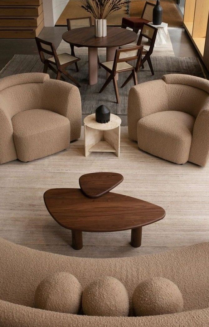 Área de estar con sillones curvos y mesa de centro de madera orgánica.